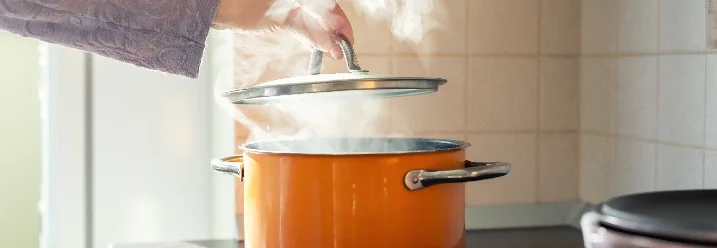 Hand nimmt Topfdeckel vom Topf